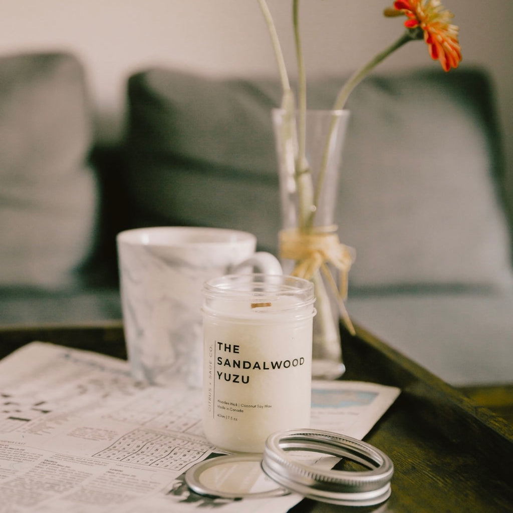 candle in a mason jar on a coffee table on a newspaper